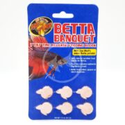 Zoomed-in image of ZOO MED BETTA BANQUET 7 DAY BLOCK 6 PACK, featuring six fish-shaped time release feeding blocks for Bettas. The blue card packaging includes a colorful Betta illustration and essential nutrient details.