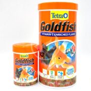 Two containers of TETRA GOLDFISH FLAKE enriched with vitamins, featuring goldfish images on a bright orange background. The larger container holds 7.06 oz and the smaller 1 oz, providing ideal nourishment for your fishs health!.