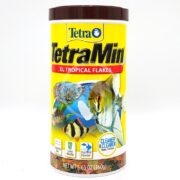 A 160g container of TETRAMIN TROPICAL FLAKE XL features vibrant fish images on a predominantly yellow and white label, promising cleaner water with less waste. The brown lid and bottom enhance the design.
