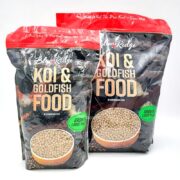 Two bags of BLUE RIDGE KOI AND GOLDFISH GROWTH LARGE PELLET food are shown. The red and black packaging, featuring a fish bowl image, is labeled for koi and goldfish, emphasizing growth benefits and large pellet size.
