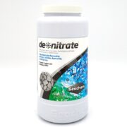 The SEACHEM DE NITRATE container, featuring gray filter media and a label with blue water bubbles, is designed to effectively remove excess nitrates, nitrites, and ammonia from aquariums.