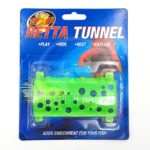 The ZOO MED BETTA TUNNEL ASSORTED COLORS packaging highlights a vibrant pink tunnel with holes, ideal for fish play and exploration. The lively backdrop features images of fish and words like Play, Hide, Rest, and Explore, ensuring enrichment for your aquarium.