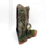 The UT RESIN MANGROVE CAVE bookend, shaped like a mangrove tree trunk and crafted from resin, features intricate details and green moss accents. A tag and a ruler indicate height on a plain white background, highlighting the natural design beautifully.