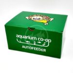 A green box labeled aquarium co-op AUTOFEEDER with white text and fish illustrations. The top of the box features a cartoon fish with large eyes.