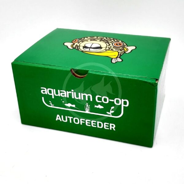 A green box labeled aquarium co-op AUTOFEEDER with white text and fish illustrations. The top of the box features a cartoon fish with large eyes.
