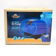 A cardboard box with a TETON DIAPHRAGM POND AIR PUMP, labeled for ponds, aquariums, and aquaculture. The box features an image of the blue pump and promotes its durability and efficiency.