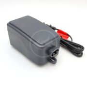 A black rectangular battery charger with a built-in power cord ending in red and black alligator clips, placed on a white background.