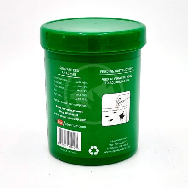 A green plastic container of aquarium fish food with a label showing feeding instructions, nutritional analysis, a recycling symbol, and aquariumcoop.com contact information. The label also has a fish feeding illustration.