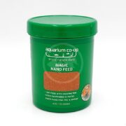 A green plastic container labeled aquarium co-op MAGIC NANO FEED with red fish food inside. Text highlights high protein, suspended in water, and suitable for nano fish, fry, and shrimp. 4 oz / 113 grams.