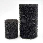 Two black, cylindrical, porous foam filters are shown standing upright against a plain white background. The filter on the left is shorter and smaller in diameter than the taller, wider filter on the right.