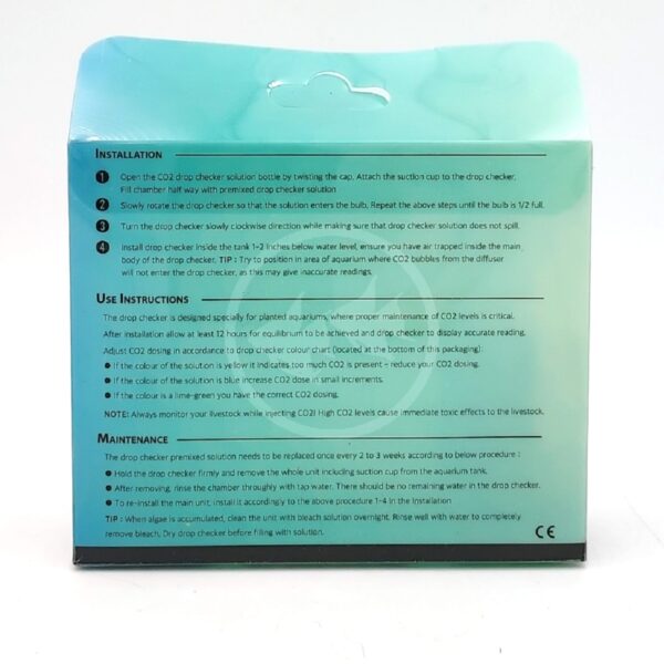 Back of a CO2 drop checker product box showing installation steps, use instructions, and maintenance tips printed in black text on a green-blue gradient background. A small cutout for hanging is visible at the top center.