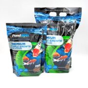 Two blue and black bags of PondMAX Premium Staple Growth Fish Food featuring images of koi fish and water, labeled as specialty food for koi and goldfish. The bags are standing upright on a white surface.