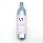 A silver metal cylinder with a white label that reads UN SYSTEMS CYLINDER lies on a white surface. The cylinder has a threaded top and a minimalist design.