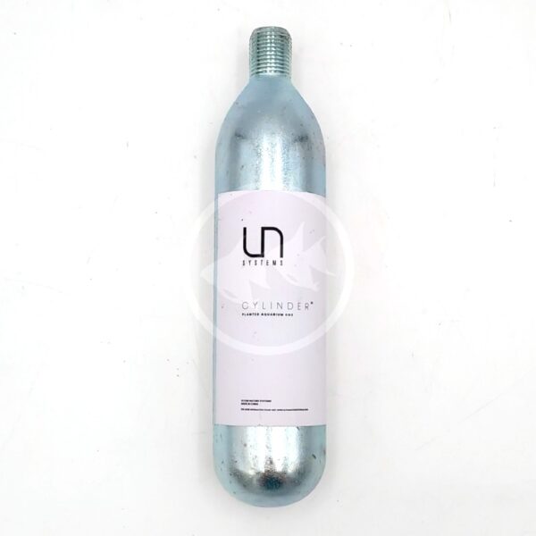 A silver metal cylinder with a white label that reads UN SYSTEMS CYLINDER lies on a white surface. The cylinder has a threaded top and a minimalist design.