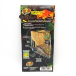 Back of Zoo Med Naturalistic Terrarium box showing labeled diagram of a terrarium setup; layers include cork flat background, water pump, Eco Earth, HydroBalls, and mesh on a forest-themed background.