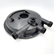 A black circular plastic component with three threaded pipe connectors extending from its side, placed on a white background. The part has multiple openings and raised areas, suggesting it is used in plumbing or machinery.