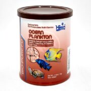 A canister of Hikari Bio-Pure FD Ocean Plankton fish food, featuring images of fish and a turtle on the label. The can is maroon with white and orange text, and is intended for aquatic pets.