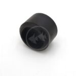 A black, cylindrical rubber cap or stopper with an open end, placed on a white surface.