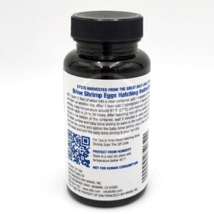 A black plastic bottle with a white label displaying brine shrimp eggs hatching instructions, a QR code, and warnings such as “PROTECT FROM HUMIDITY” and “NOT FOR HUMAN CONSUMPTION.”.