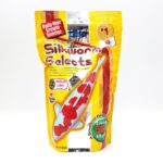 A yellow bag of HIKARI SILKWORM SELECTS TREAT 17.6 OZ fish food shows a large koi image, with red and white text, and labels such as Daily Diet Growth Booster and 50% Silkworm on the packaging.