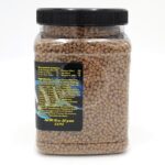 A clear plastic jar with a black lid, filled with small brown pellets. A label on the jar displays nutritional information and ingredients in yellow and white text on a black background.