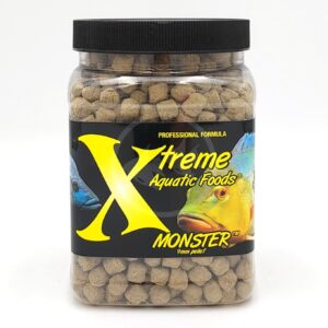 A clear plastic jar filled with round fish food pellets, labeled Xtreme Aquatic Foods Monster 9mm Pellet with images of two colorful fish and a large yellow X on the black label.