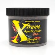 A black plastic jar labeled Xtreme Aquatic Foods ShrimpE with a yellow X, images of colorful shrimp, and the text Professional Formula and 2.4mm sinking stick on the front.