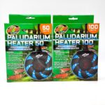 Two boxes of Zoo Med Paludarium Heaters are displayed side by side. The left box is 50 watts and the right box is 100 watts. Both feature images of the heaters and have green and orange accents with animal images.
