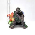 The PP RESIN SUNKEN GARDENS BELL is a decorative aquarium ornament shaped like a hollow, mossy tree stump with faux red and yellow flowers, shown before a ruler for scale.