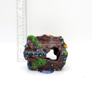 The PP RESIN TREASURE CHEST is a small decorative ornament with metal-like bands, green moss accents, and a central hole. Displayed before a ruler for scale, this resin chest stands approximately 10 cm tall.