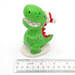 The PP RESIN HOLIDAY DECOR HOLR5B is a small green dinosaur figurine in a red and white Santa hat, made from Penn Plax resin, standing about 2 inches tall on a white base—ideal for festive holiday decor.