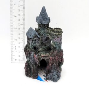 The PP RESIN WIZARDS CASTLE SMALL RRW6 is a resin figurine with two stone-like towers, painted grey, green, and red. Shown beside a ruler, its height is about 12 cm.