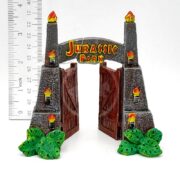 The PP RESIN JURASSIC PARK GATES SMALL JPR6W is a 4-inch resin model with open gates, flickering torches, and green leaves at the base. A ruler shows its size, making it a detailed miniature for collectors.