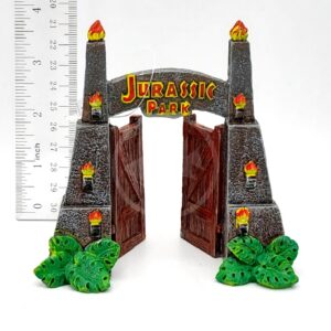 The PP RESIN JURASSIC PARK GATES SMALL JPR6W is a 4-inch resin model with open gates, flickering torches, and green leaves at the base. A ruler shows its size, making it a detailed miniature for collectors.