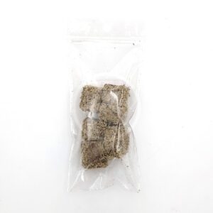 A clear plastic bag containing several small, brown, fibrous cubes is placed on a white background.