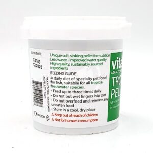 White container of aquatic fish food with a green and white label displaying feeding instructions, warnings, and product information, including Not for human consumption in red text. A barcode and recycling symbol are also visible.