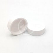 Two small, round, white plastic AU PENN PLAX UNDER GRAVEL FILTER CAPS sit on a plain white surface: one upright with the lid, the other lying on its side with the open end facing forward.