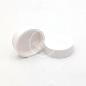 Two small, round, white plastic AU PENN PLAX UNDER GRAVEL FILTER CAPS sit on a plain white surface: one upright with the lid, the other lying on its side with the open end facing forward.